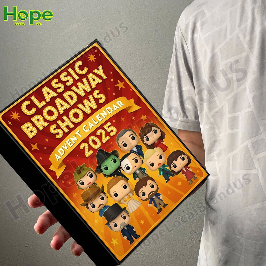 A person holding a square shaped advent calendar box with a Broadway theme!