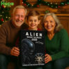 An older man an older woman and a young boy smile happily while holding the Alien Advent Calendar 2025 box together!