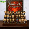The Metallica Advent Calendar 2025 box and all 24 collectible figures are displayed on a wooden stand with a festive Christmas lights background!