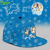 A blue baseball cap featuring Bluey and Bingo alongside the Detroit Lions logo. The cap has a fun design with the animated characters in sports outfits.